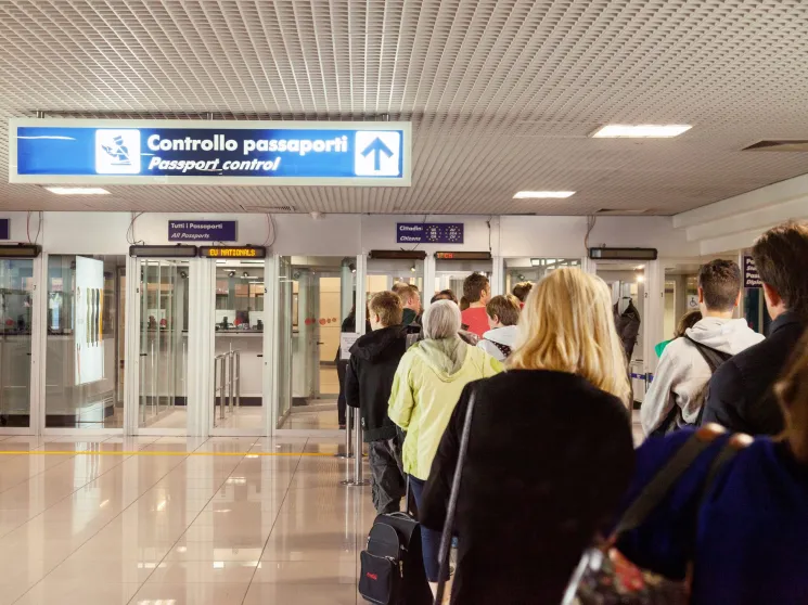 People queuing at passport control booths in an airport terminal