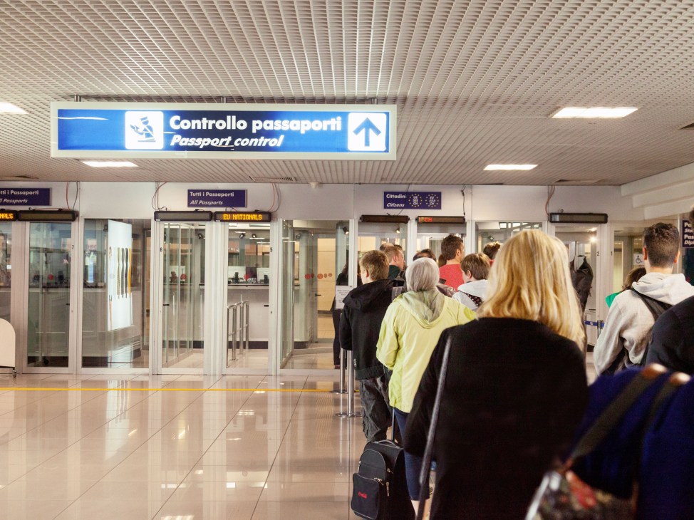 People queuing at passport control booths in an airport terminal