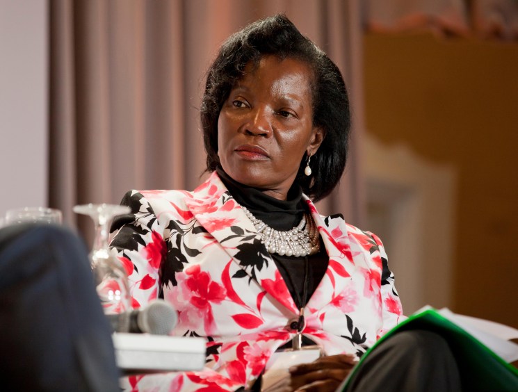 Jennifer Musisi wearing a floral blazer and pearl necklace seated at what appears to be a conference or interview setting