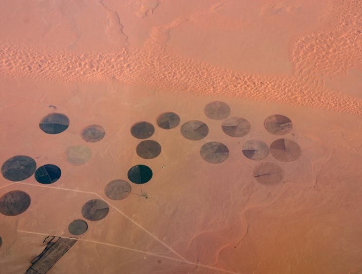 Aerial view of circular agricultural fields creating geometric patterns across an arid desert landscape