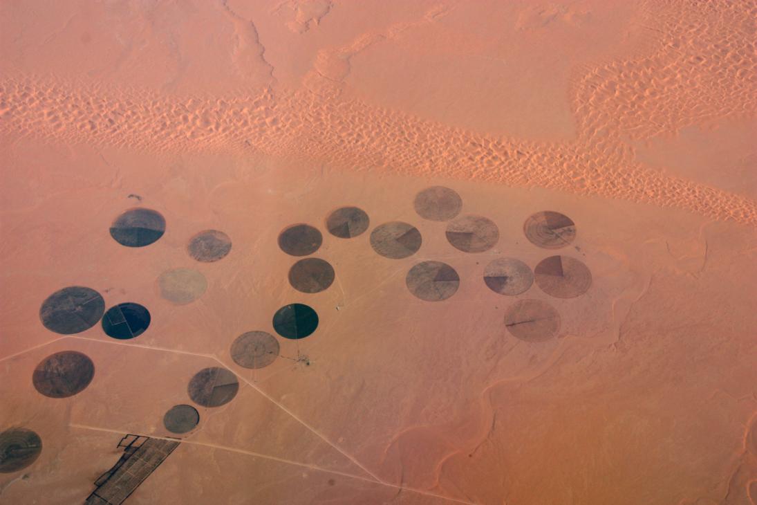 Aerial view of circular agricultural fields creating geometric patterns across an arid desert landscape