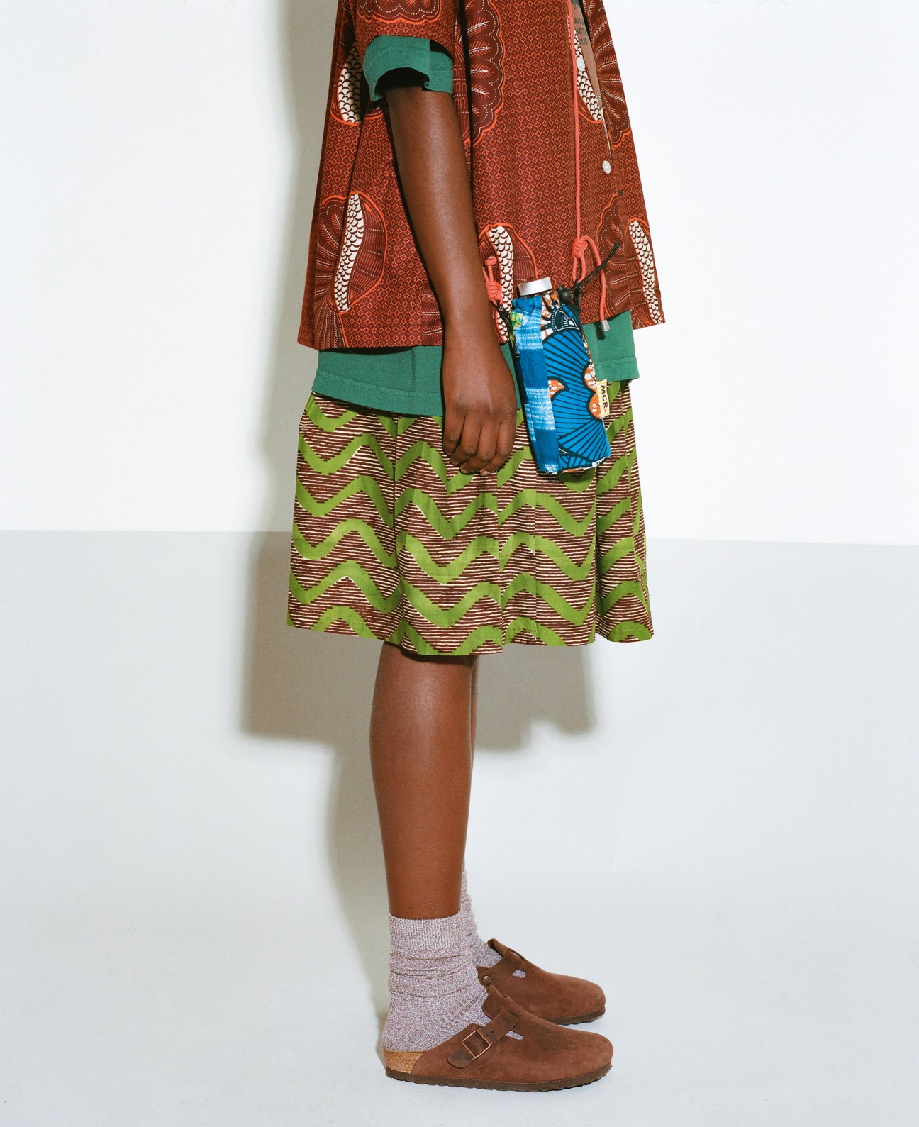 Model wearing Maison Château Rouge clothing with colorful African wax fabric patterns and green accents