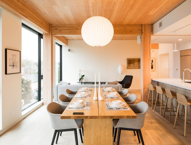 Interior of a wooden apartment with dining table, kitchen and living area showcasing timber construction.