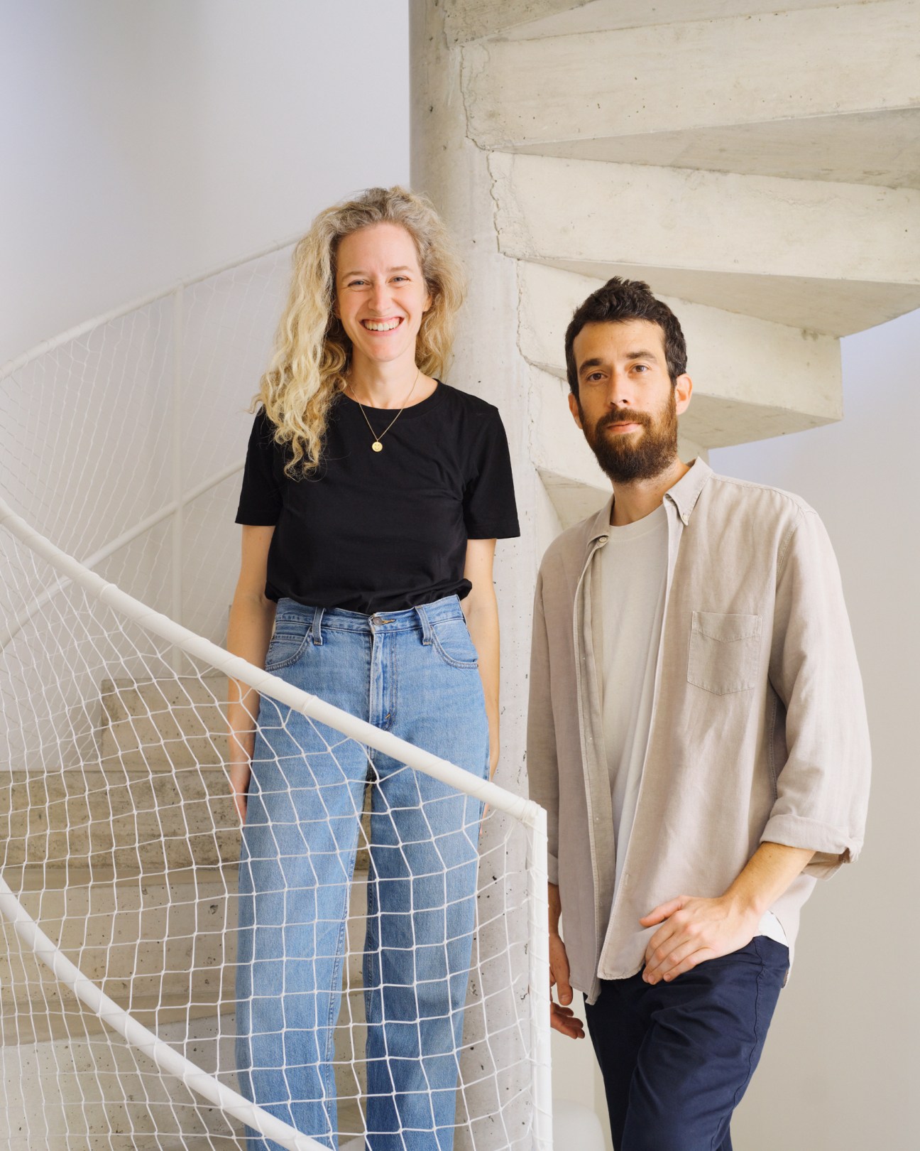 Nina Ordeig Masó and David Martí Vilardosa standing on concrete stairs with white mesh railing in their modern home