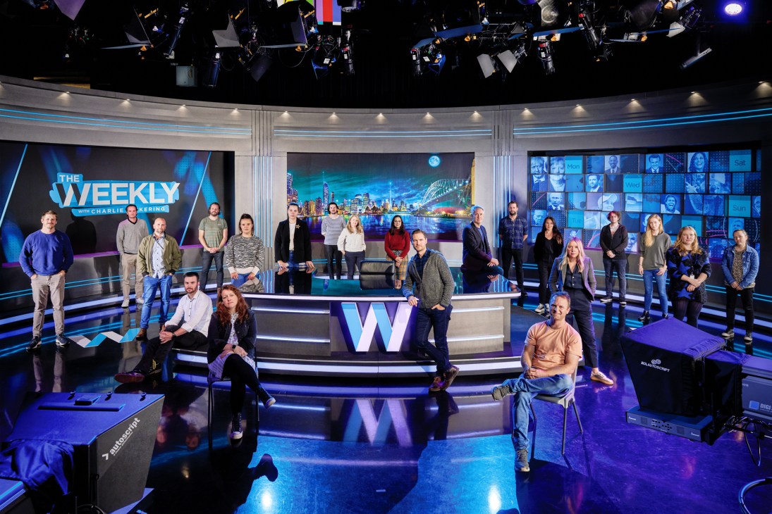 Charlie Pickering and production team members pose in The Weekly television studio set