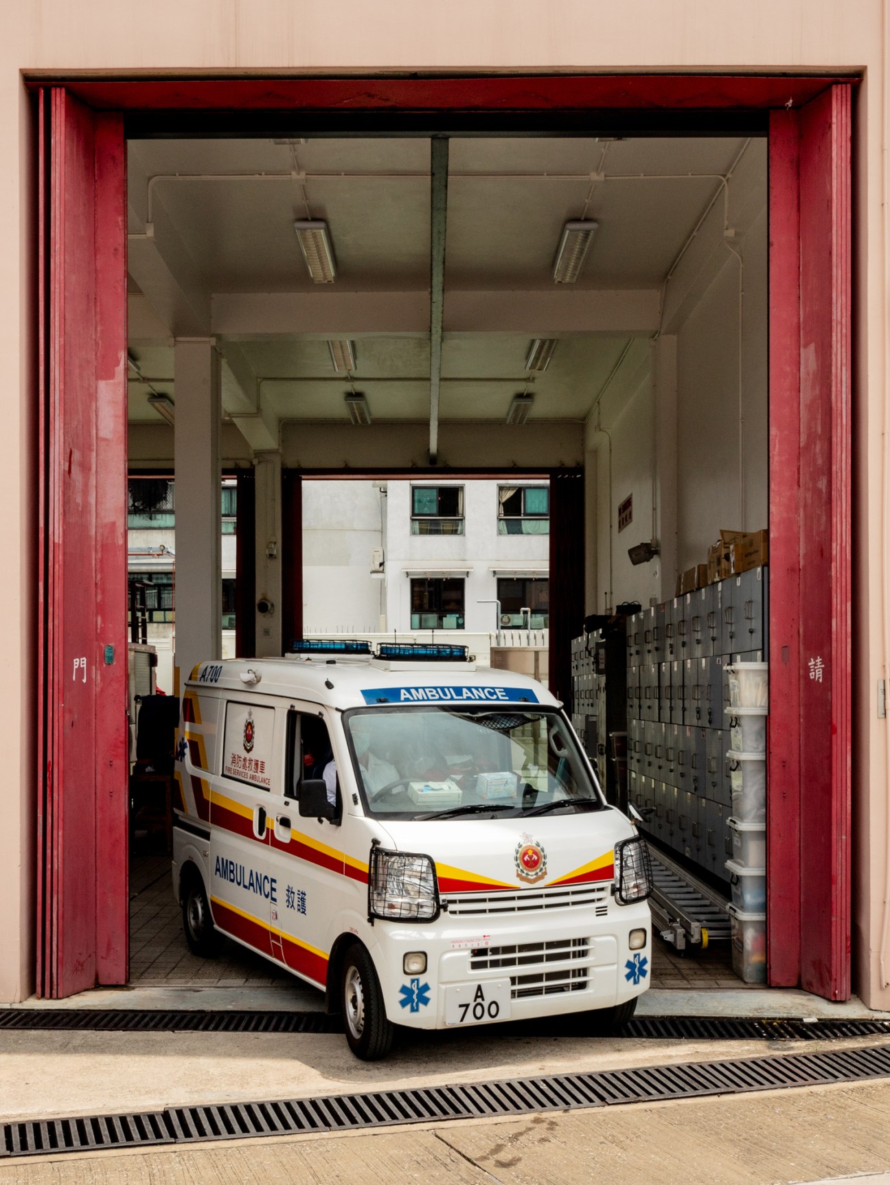 White ambulance with red and yellow stripes parked in fire station garage bay