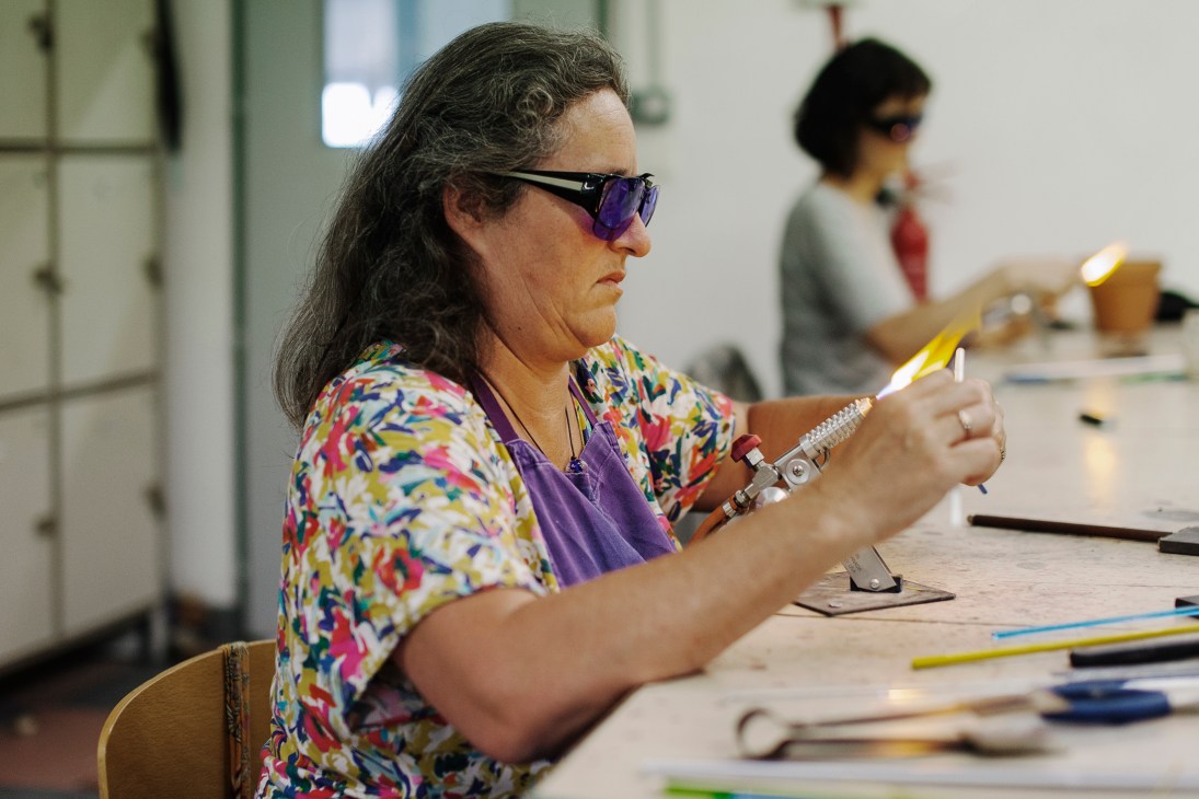 Student concentrating while working with molten glass at French training centre