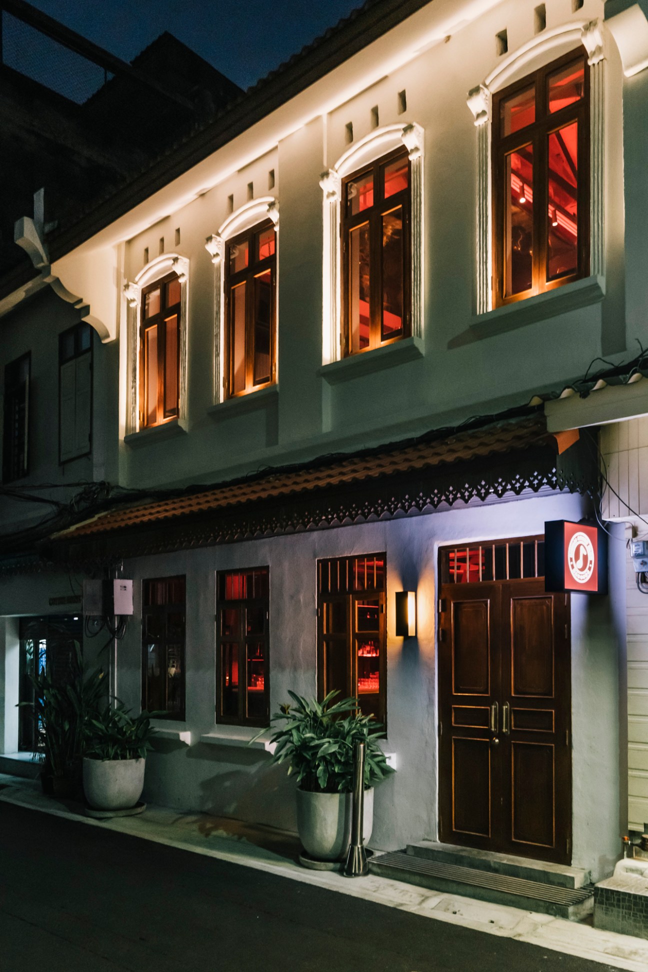 Night view of illuminated colonial-style shophouse building with traditional architecture and warm lighting