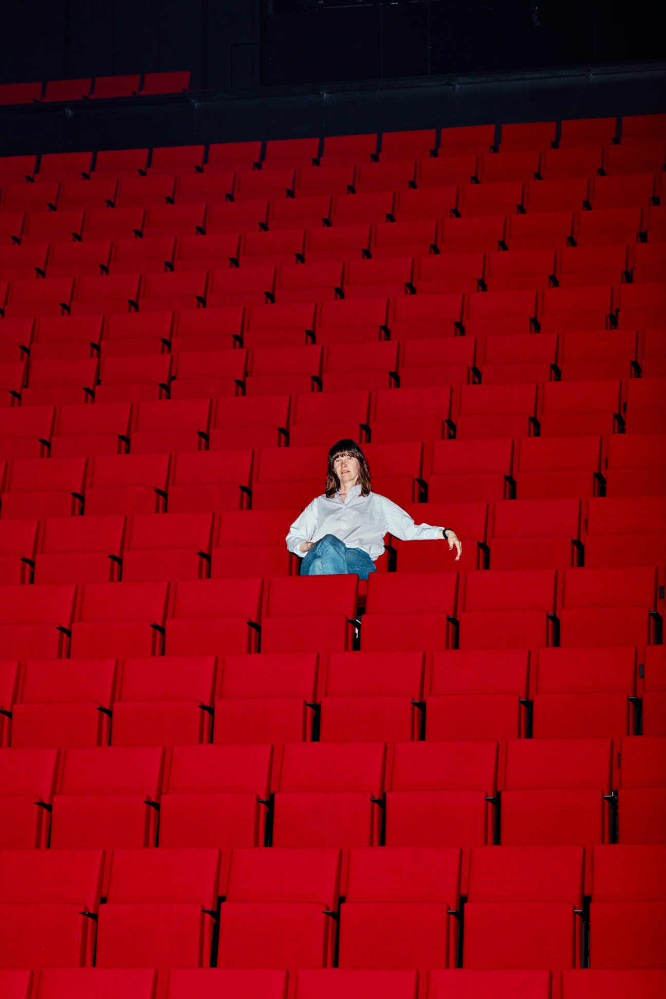 Niki Matheson, managing director of Dance House Helsinki, sitting alone among rows of empty red theater seats
