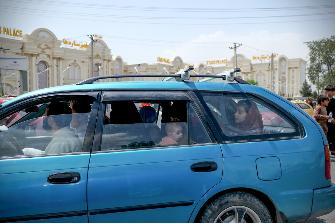 Families with children in a blue car traveling to Kabul airport for evacuation flights