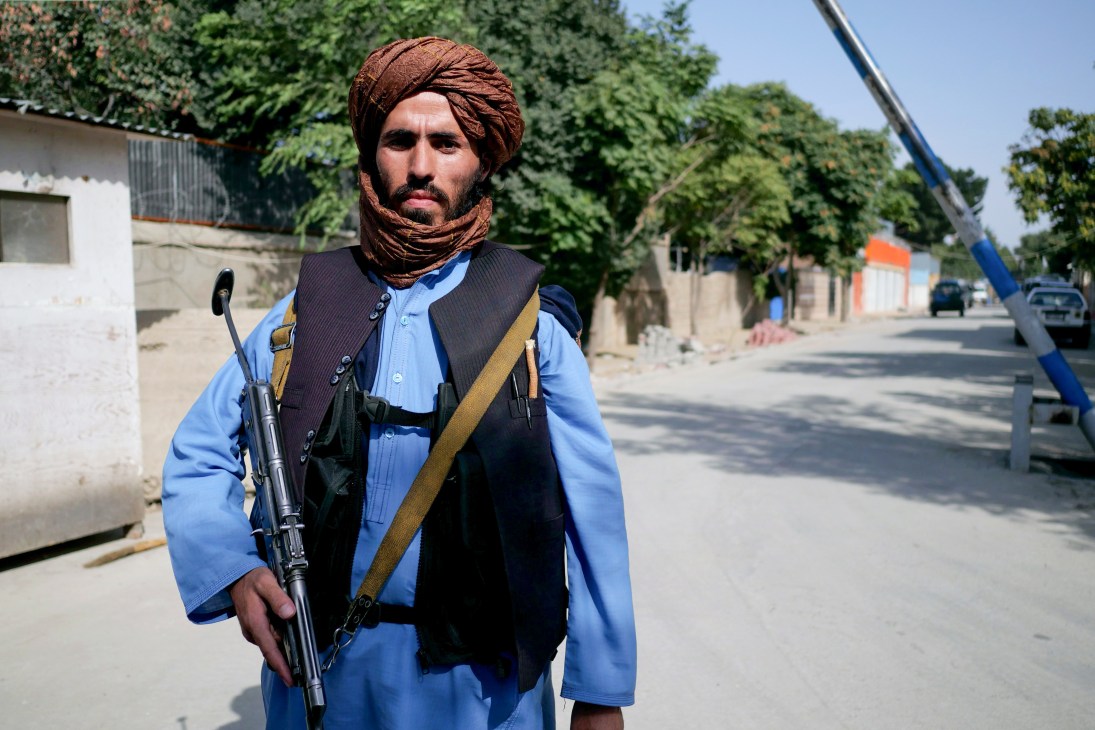 Taliban fighter Mohammad Haroon, 22, wearing a brown turban, light blue shirt, dark vest and carrying a rifle on a Kabul street