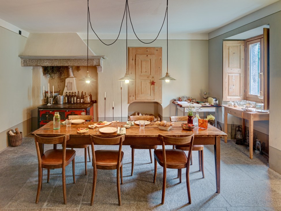 Interior of Pontisella bed and breakfast in Stampa with wooden dining table, leather chairs, fireplace and pendant lighting.