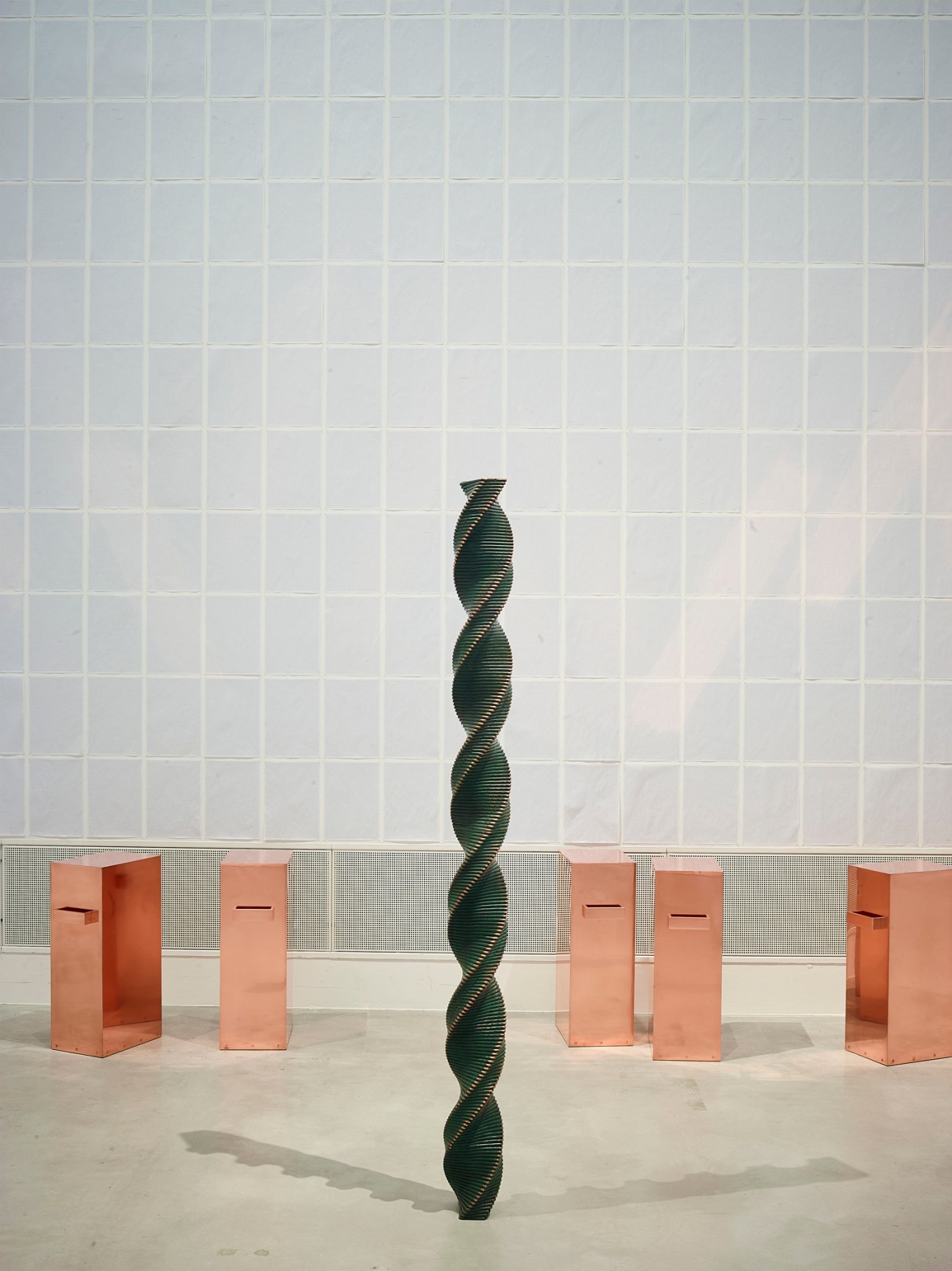 Contemporary art installation with black twisted column sculpture surrounded by copper-colored geometric blocks