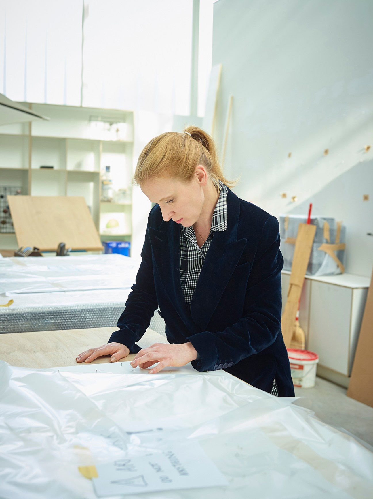 Artist Alicja Kwade working in her studio examining documents or papers on a table