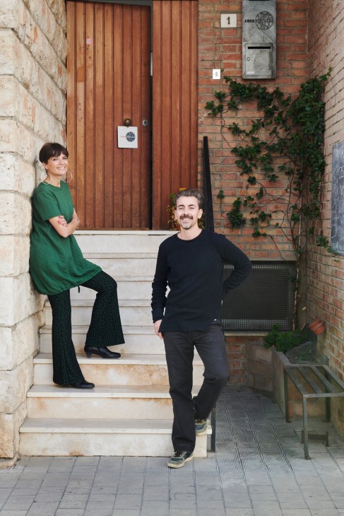 Architect Andrea Paoletti and his partner Maria Stella stand outside Casa Netural's brick entrance.