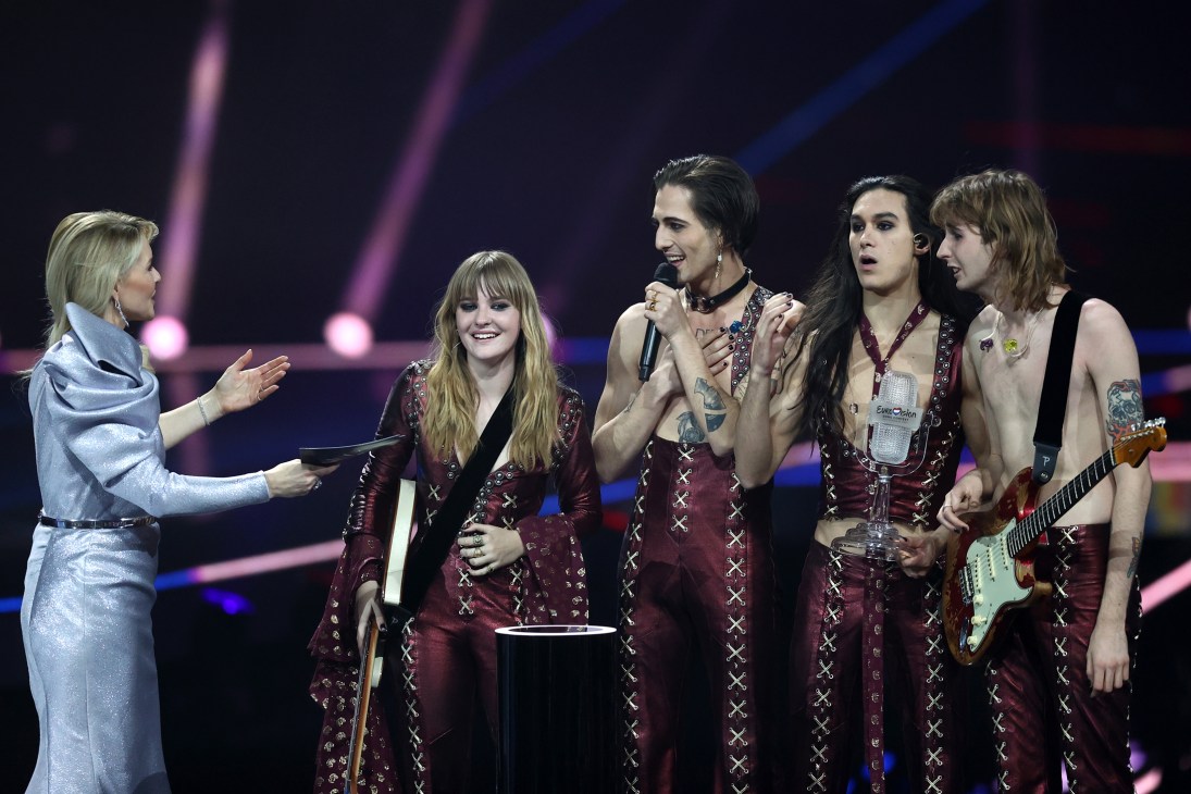 Italian rock band Måneskin performing on stage at an awards ceremony with matching burgundy outfits