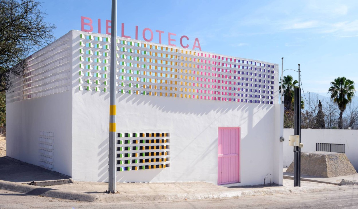 Modern white library building with colorful rainbow-patterned windows and pink entrance door