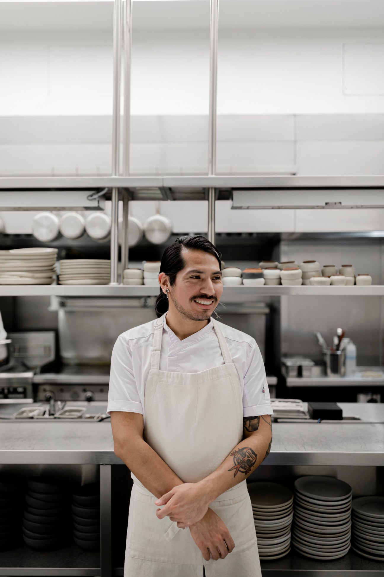 Chef Alvaro Vasquez smiling in kitchen whites and apron in a professional kitchen