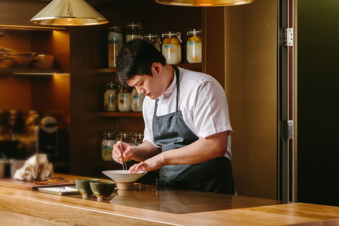 Chef Barry Quek working at a wooden counter in a professional kitchen setting