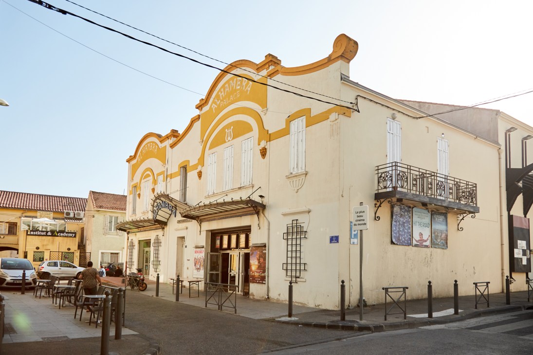 Historic facade of Alhambra cinema building with ochre-yellow accents and classic French architecture