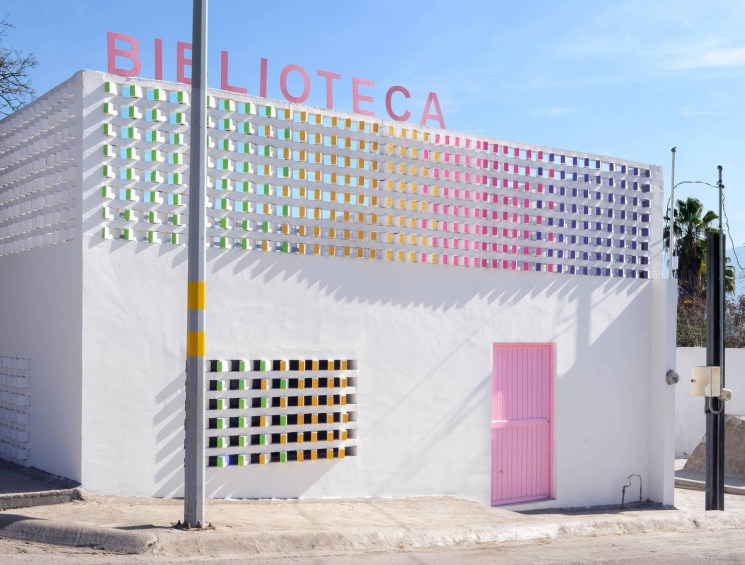 Colourful library building facade with a grid of pastel tiles and pink door.