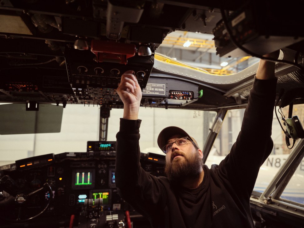 Technician with beard and glasses working on aircraft instrumentation in cockpit