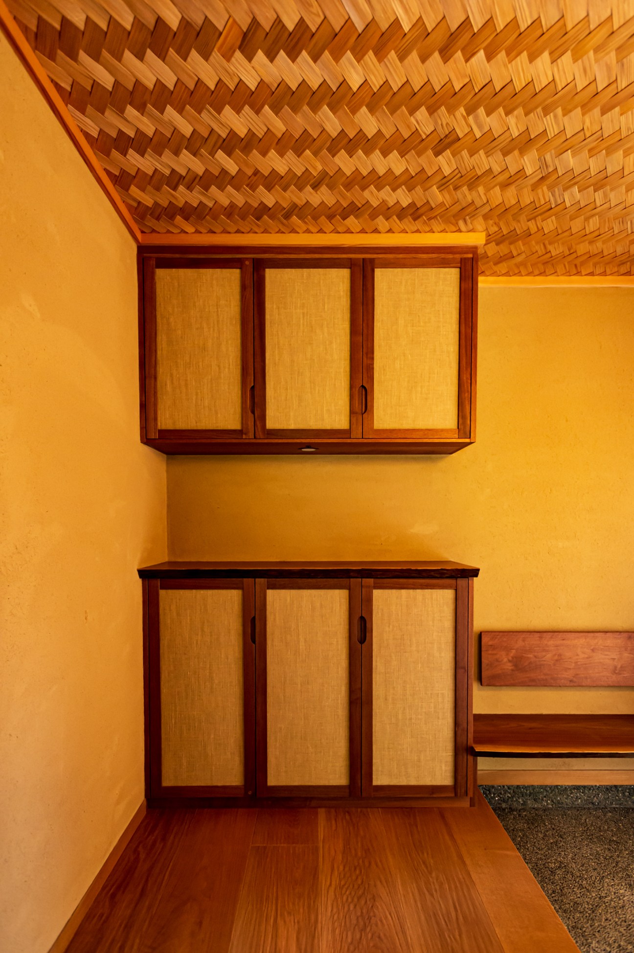 Built-in wooden cabinet with woven bamboo panels and geometric woven ceiling detail