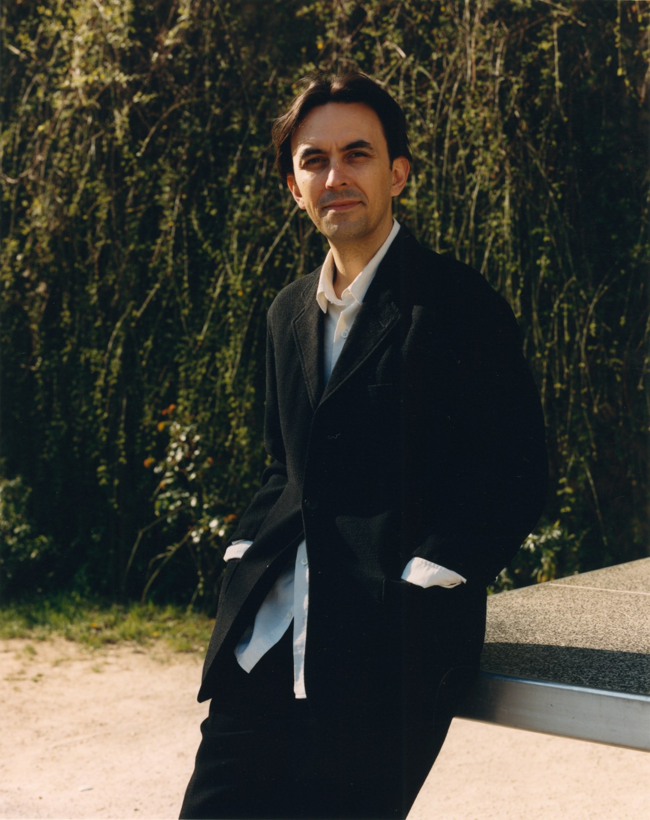 Clément Delépine standing outdoors in dark coat with foliage background