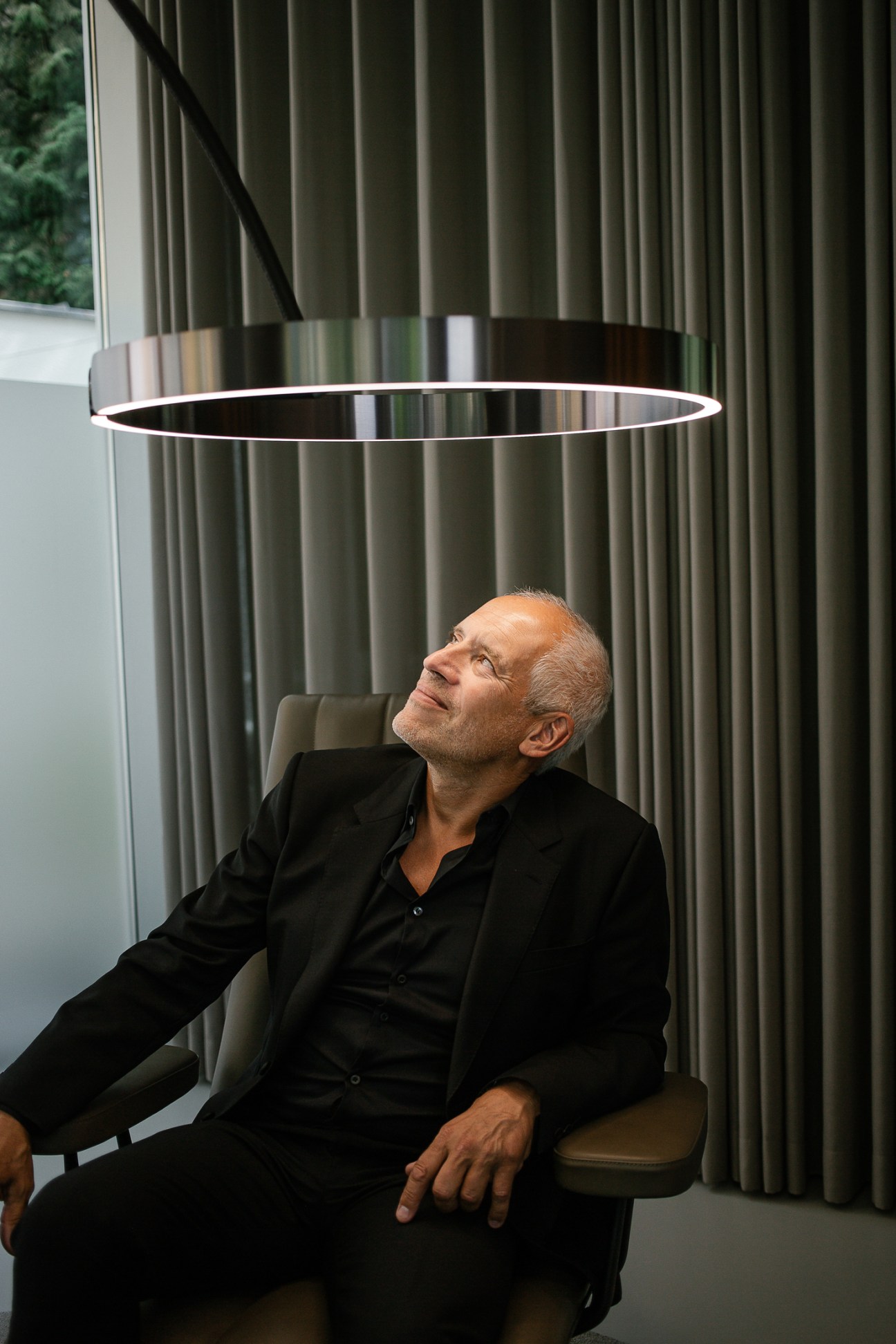 Axel Meise looking up at a circular Mito light fixture in his Munich office