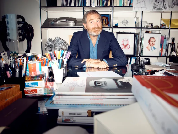 Fabrizio Buonamassa Stigliani sitting at his desk in his office with shelves of books and design materials behind him