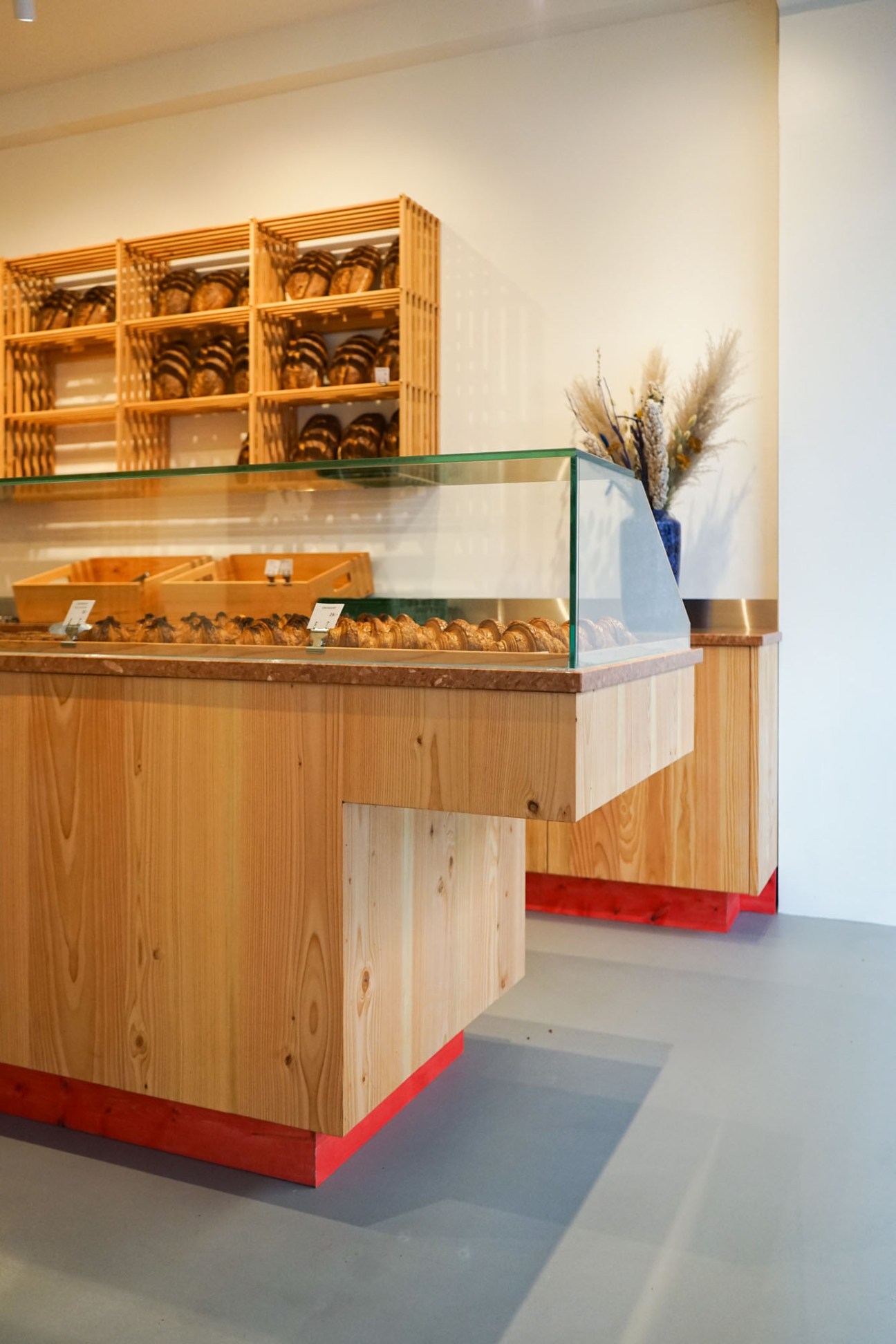 Modern bakery display case with wooden shelving system holding various baked goods and pastries