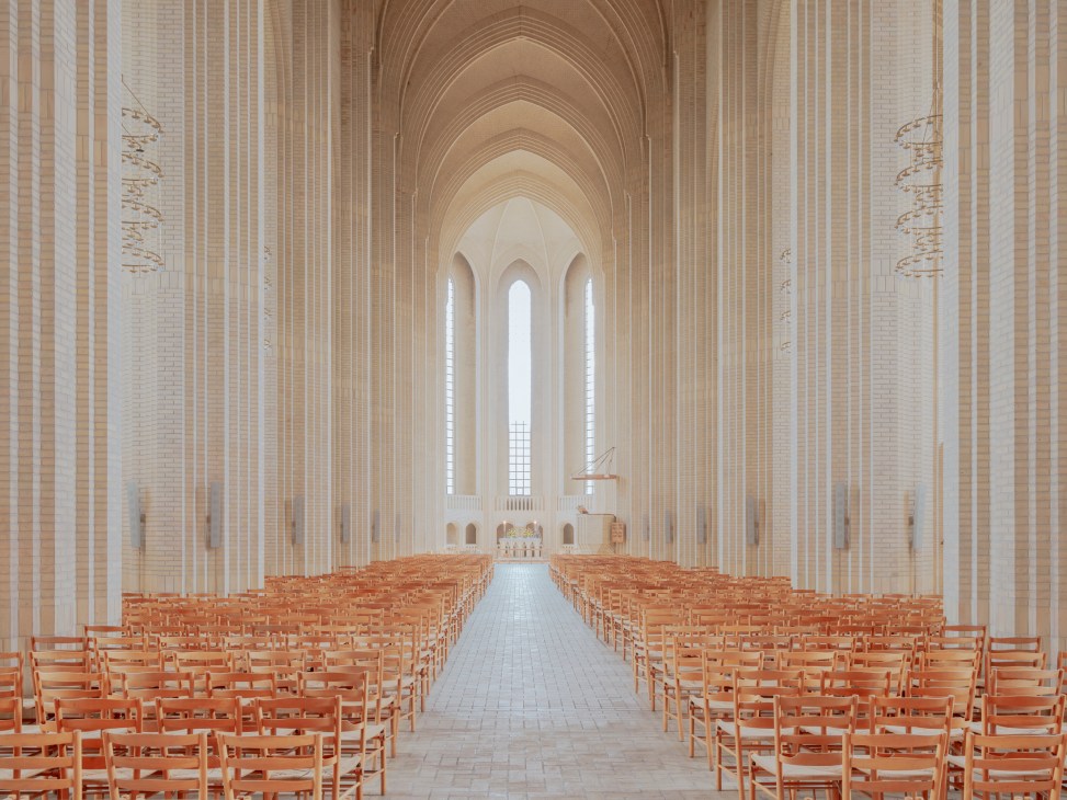 Interior view of Grundtvig's Church showing soaring yellow brick nave with wooden chairs and Gothic arches