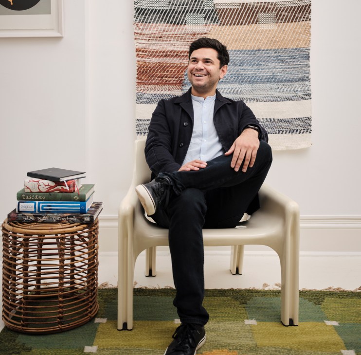 Taymoor Atighetchi sitting in a chair in a bright office space with books and decorative items