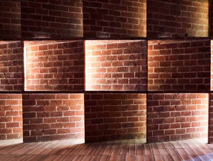 Interior view of Cristo Obrero church showing dramatic natural light filtering through curved brick walls and windows