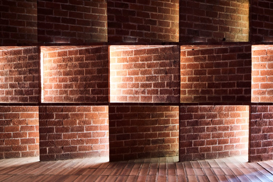 Interior view of Cristo Obrero church showing dramatic natural light filtering through curved brick walls and windows