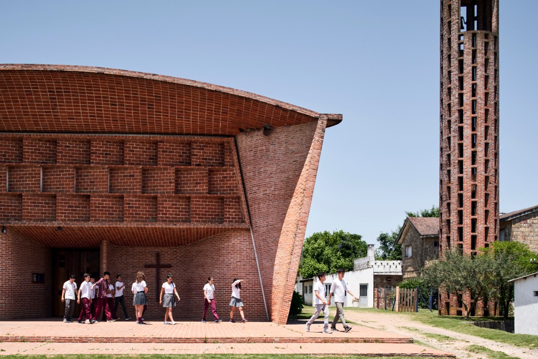 Exterior view of Cristo Obrero church with curved brick walls and students walking outside