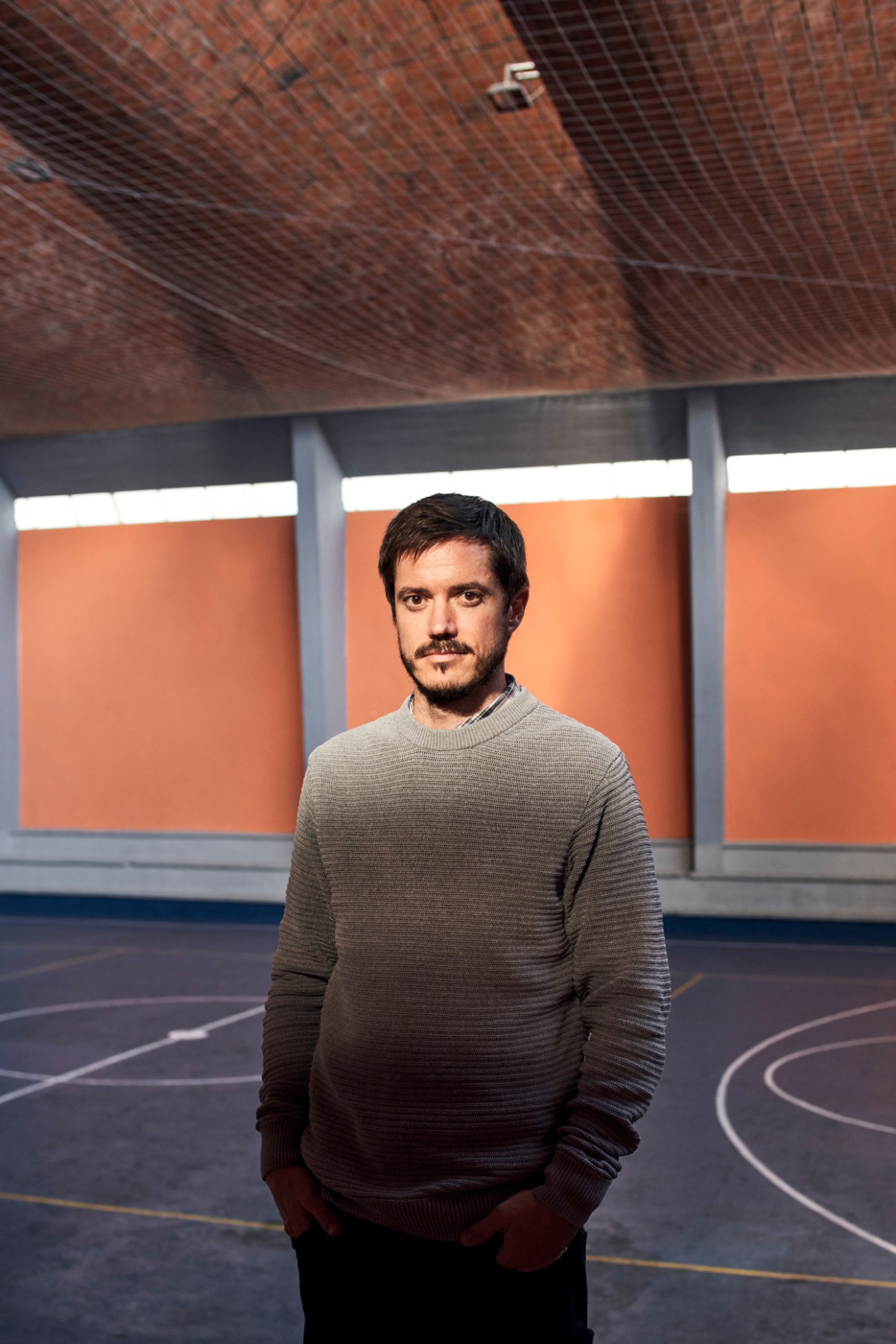 Portrait of Agustín Dieste, a young man with dark hair and mustache wearing a gray sweater