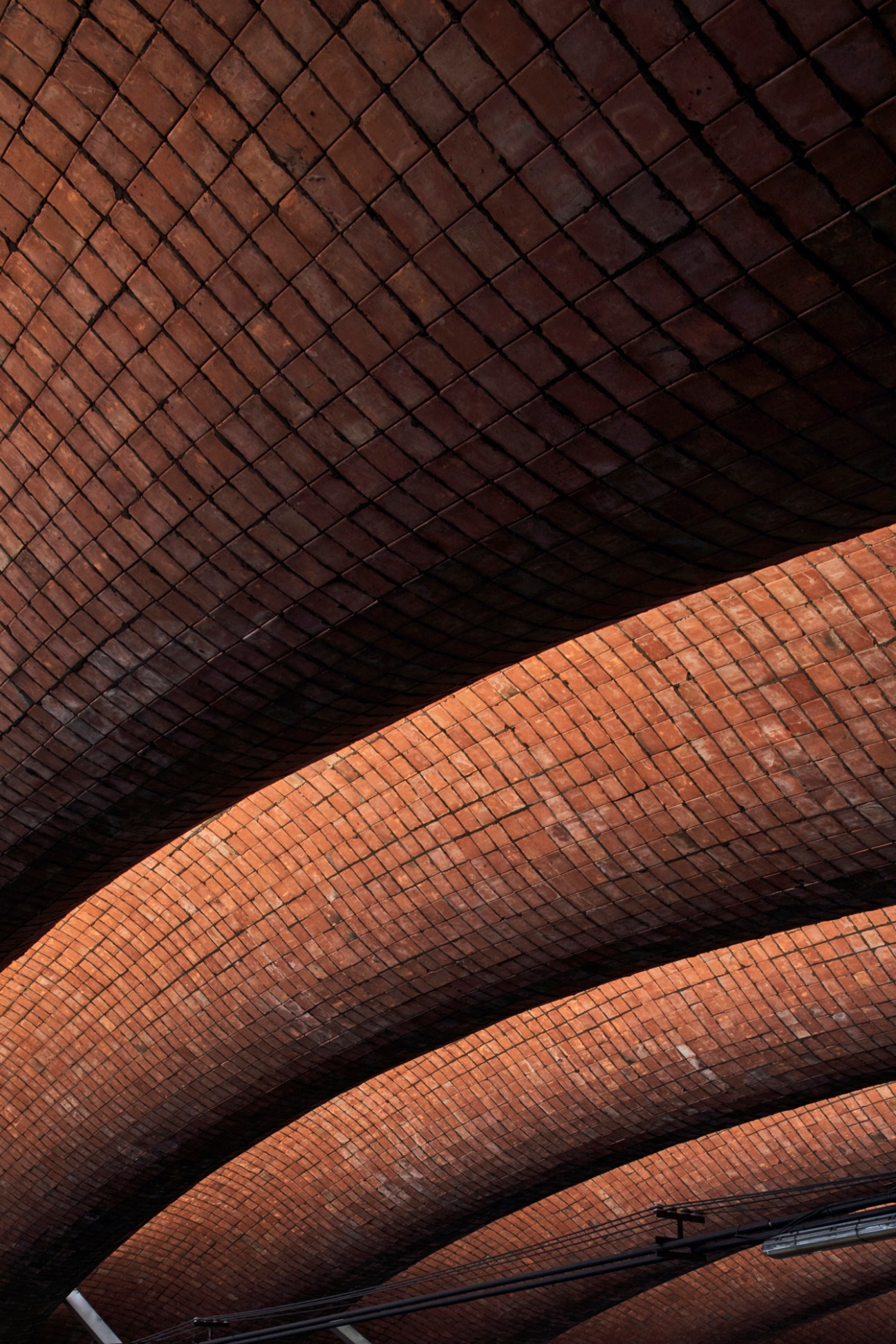 Interior view of curved brick vaulted ceiling showing undulating wave-like architectural pattern