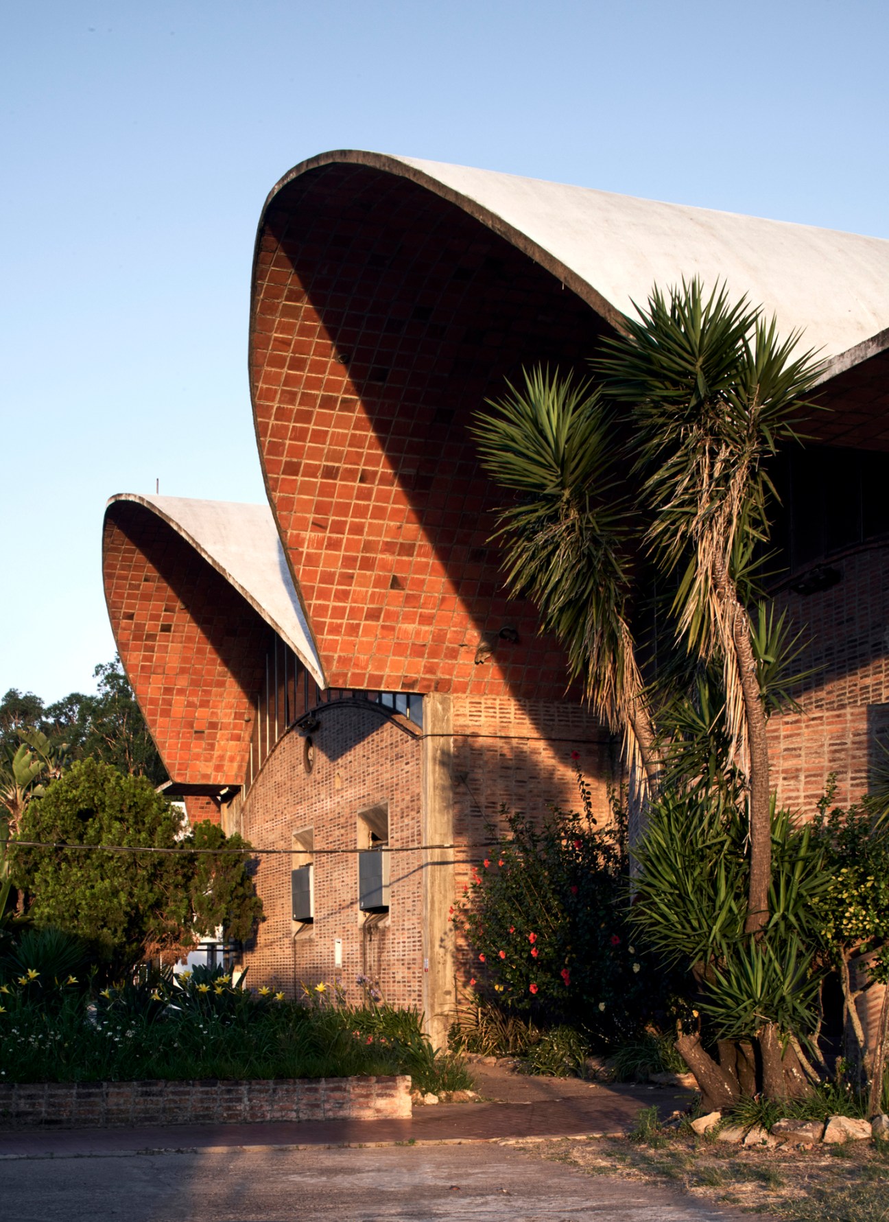 Wide industrial building with curved undulating brick roof structure and minimal support columns