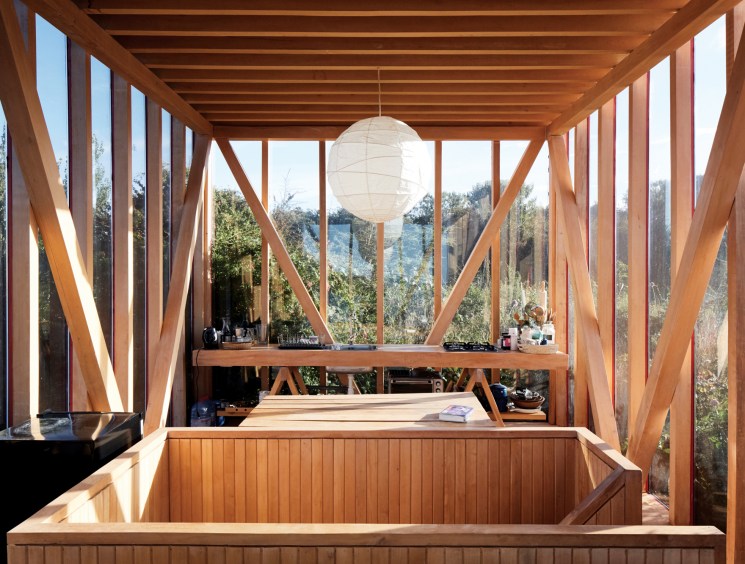 Interior view of the cabin's upper level showing wooden beams and glass walls with views to the forest