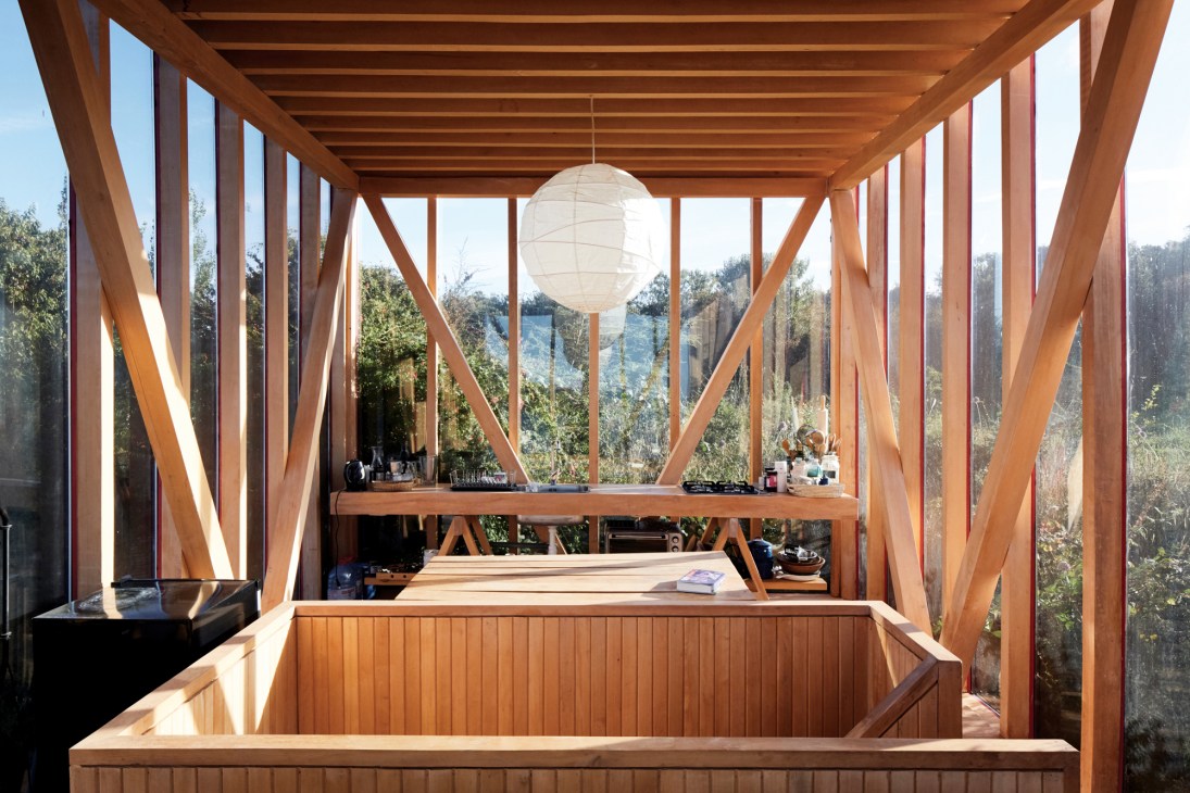 Interior view of the cabin's upper level showing wooden beams and glass walls with views to the forest