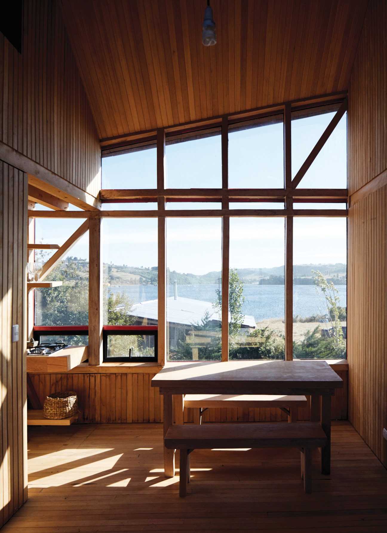 View from inside the communal area looking out through large windows to the water and forest beyond