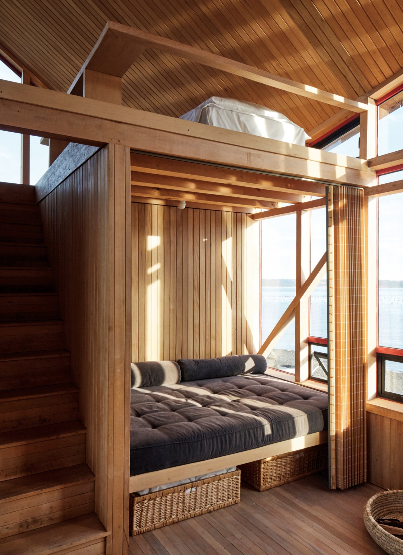 Wooden bunk bed with built-in canopy frame and wicker storage baskets underneath in rustic cabin interior
