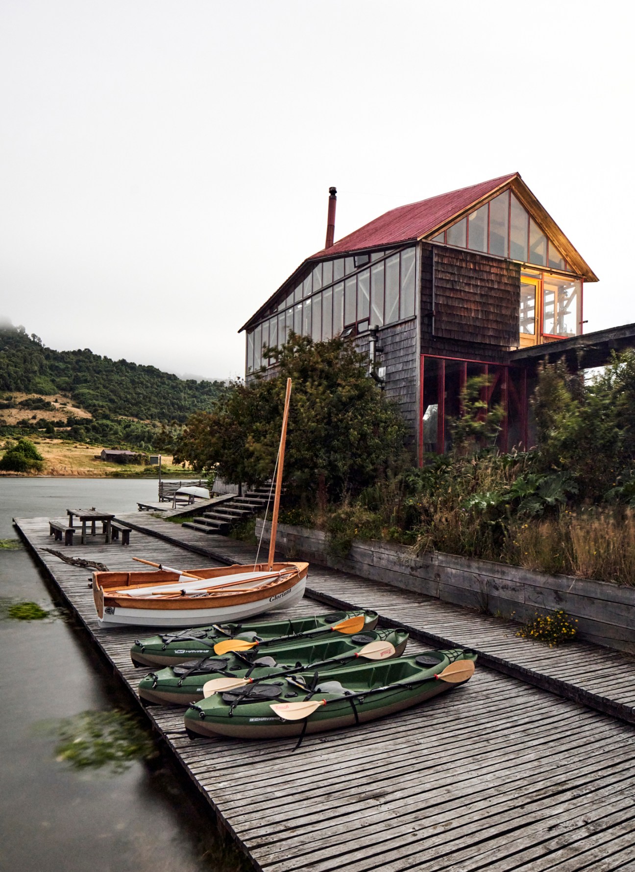 Red wooden structures on stilts built directly on the shoreline at the water's edge