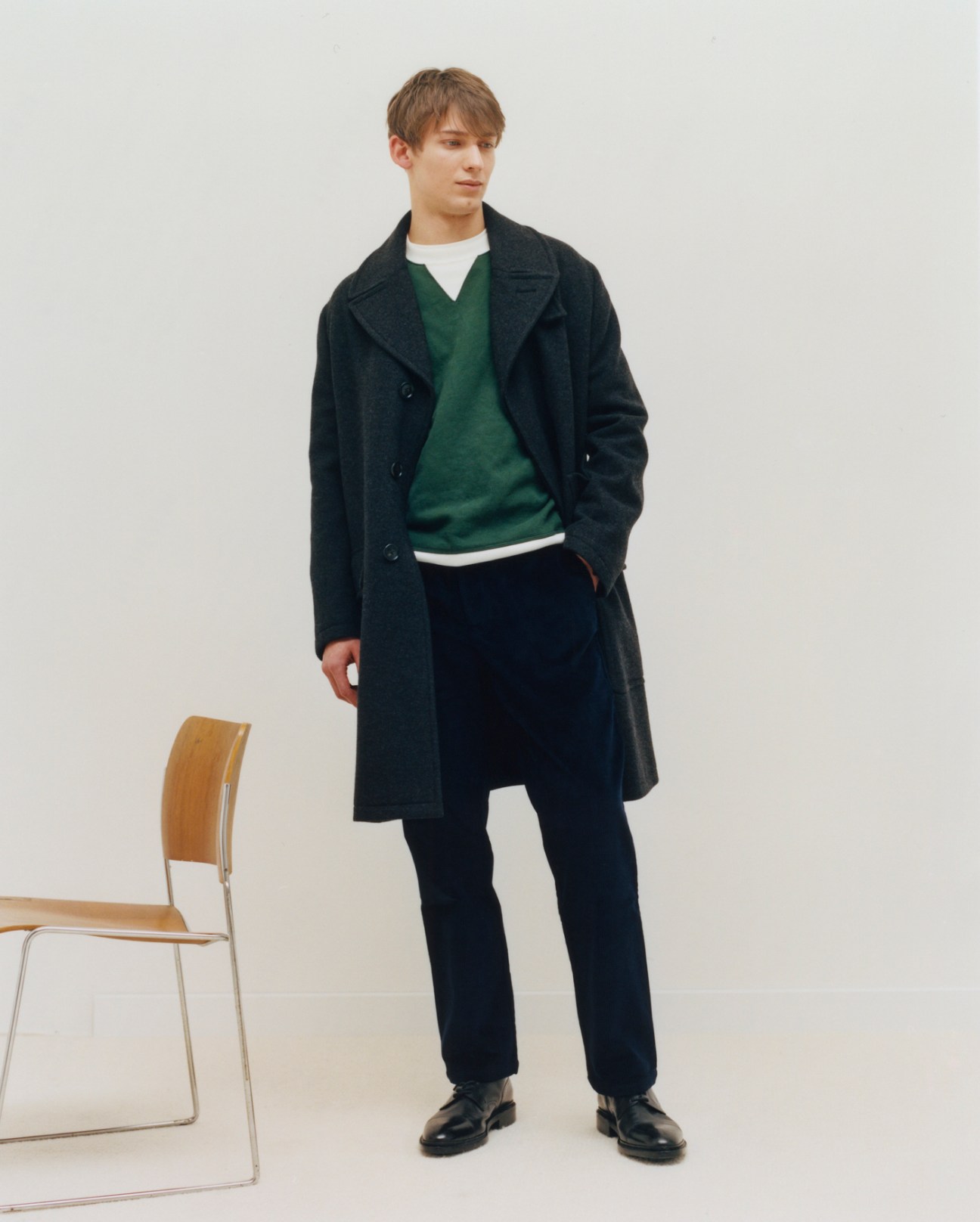 Model wearing coat by Hermès, jumper by Fursac, t-shirt by Uniqlo, trousers by De Bonne Facture, and shoes by John Lobb
