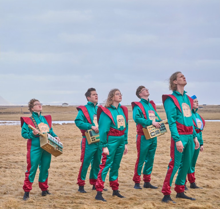 Icelandic band Daði og Gagnamagnið wearing matching green and red tracksuits in a field
