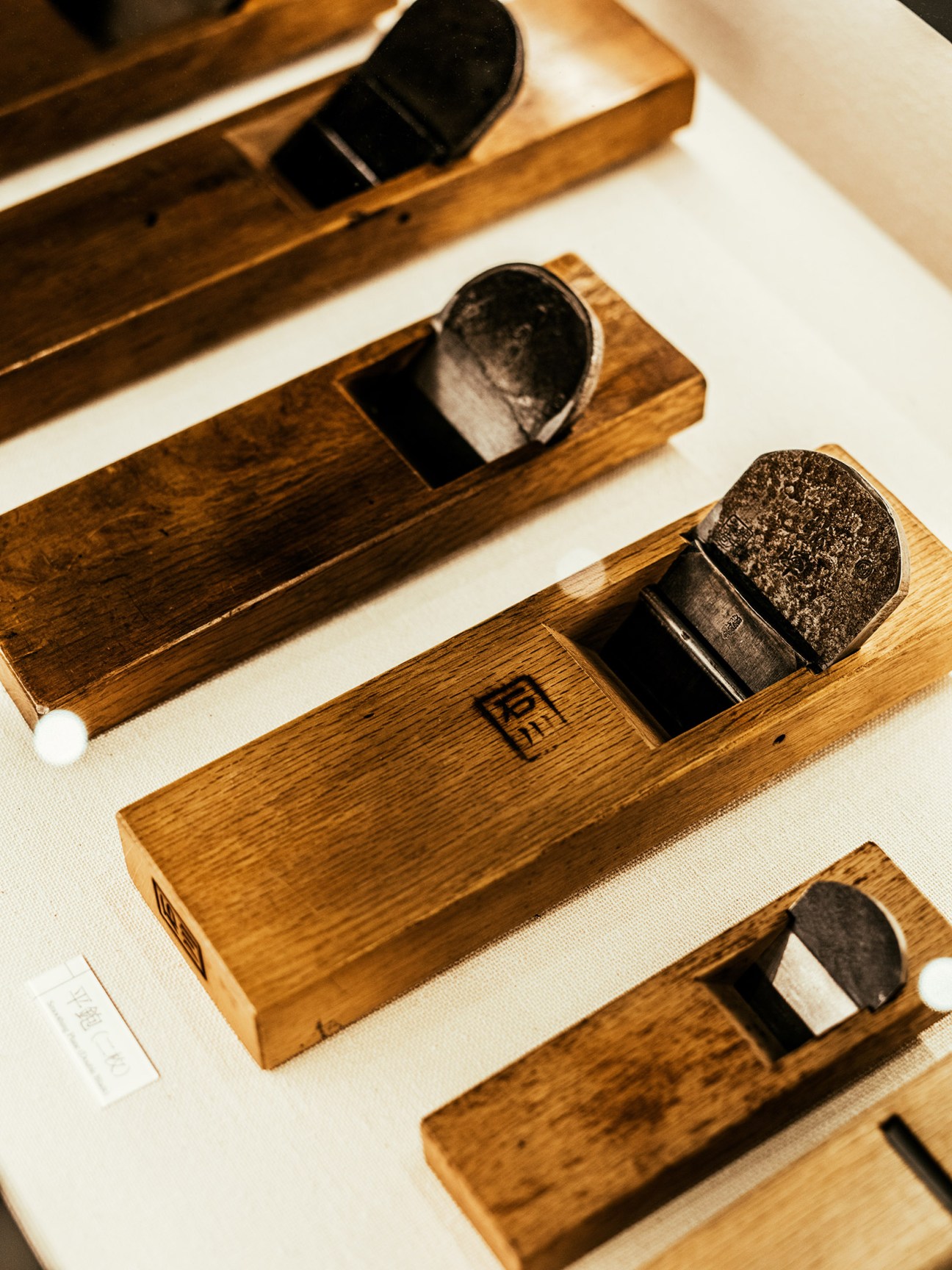Traditional Japanese wooden planes (kanna) with dark metal blades displayed on white surface.