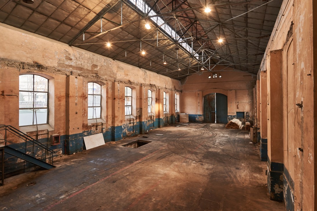 Interior of historic brick building with arched windows and industrial ceiling before renovation into contemporary art center
