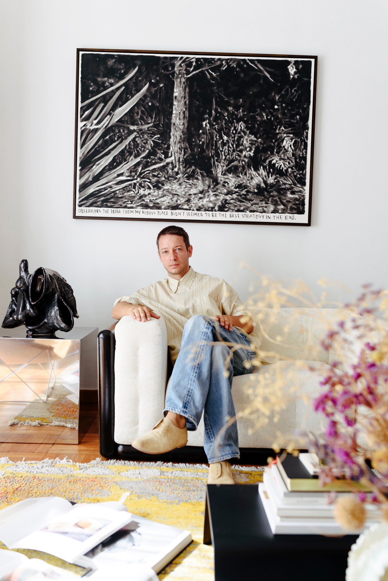 Damir Doma sitting in modern chair in minimalist interior with black and white artwork on wall behind him