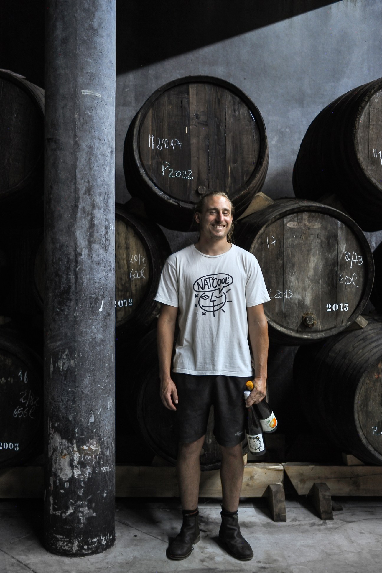 Daniel Niepoort standing in wine cellar surrounded by large wooden barrels marked with years and codes